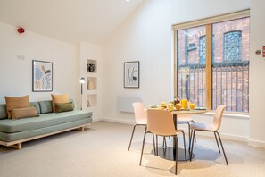 Una sala moderna con sofá, sillas, mesa de comedor y obras de arte en las paredes.