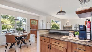 A modern kitchen with wooden cabinets, a granite countertop, and a dining area with a table and chairs. - Modern 2BR in DT Renton, 3 AC, WS 95, Shop&Parks (Renton)