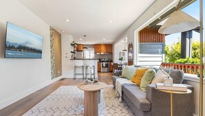 A modern living room with a sofa, coffee table, and a view of the kitchen and dining area. - Modern 2BR in DT Renton, 3 AC, WS 95, Shop&Parks (Renton)