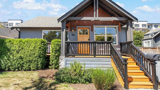 A two-story house with a wooden front door, a balcony, and a staircase leading to the second floor. - Modern 2BR in DT Renton, 3 AC, WS 95, Shop&Parks (Renton)