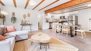 A spacious living area with a sofa, coffee table, and kitchen in the background.