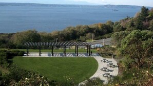 A park with a gazebo, picnic tables, and a view of the sea.
