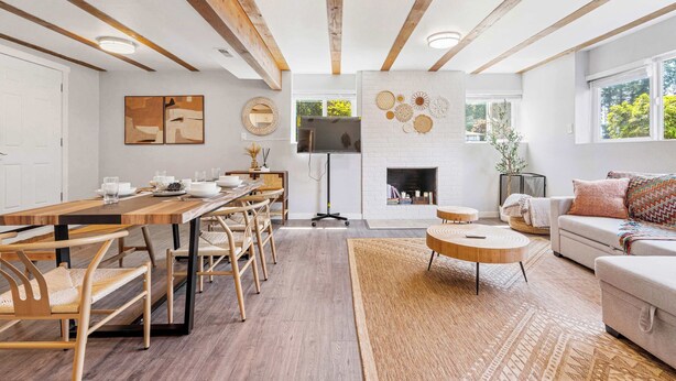 A spacious living room with a wooden dining table, sofas, and a fireplace.