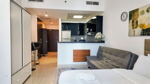 Een moderne hotelkamer met een bed, een bank, een kitchenette en een badkamer.