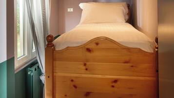 A bunk bed with a wooden headboard and a window with curtains.