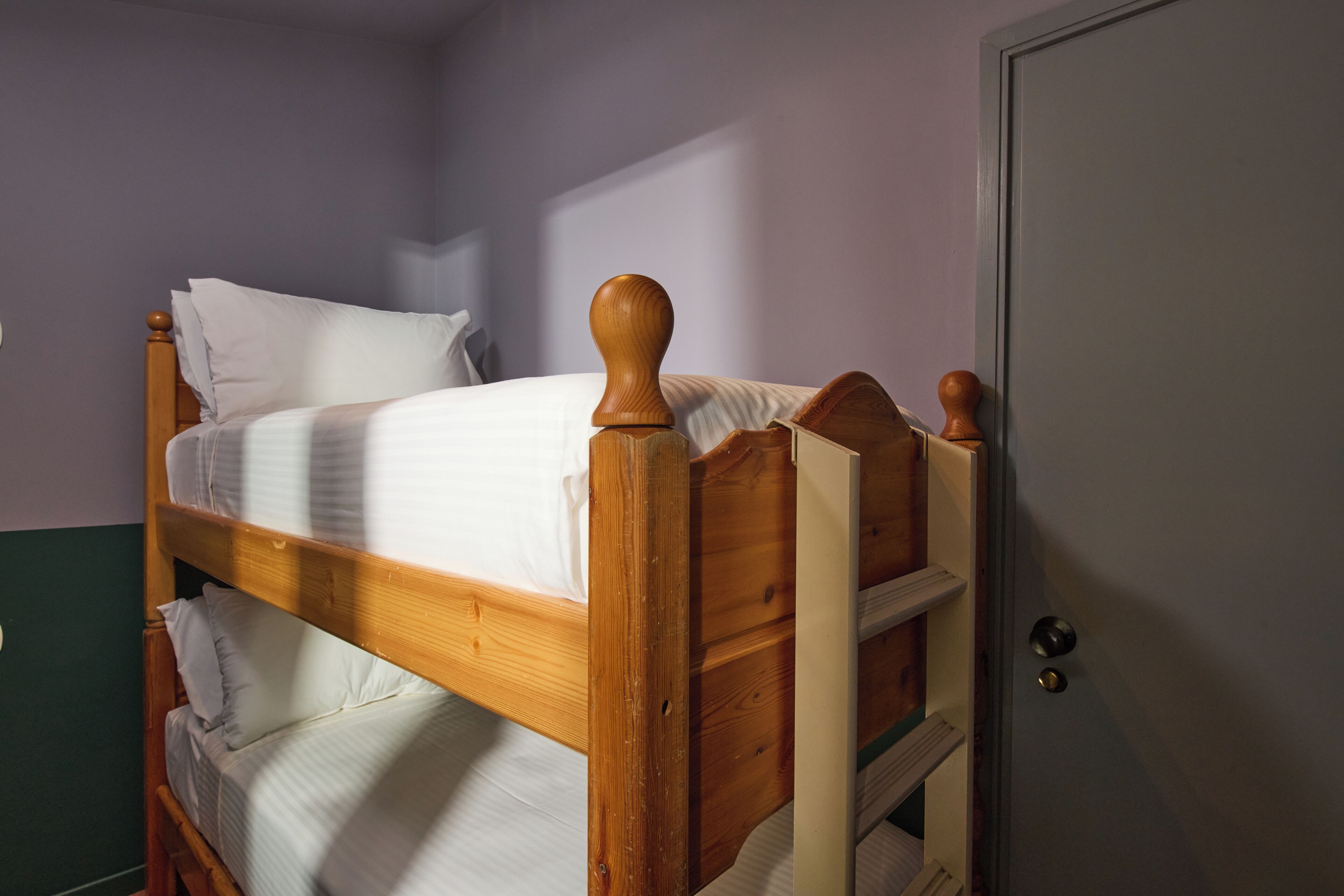 Una cama de madera individual con cabecera, una mesita de noche y una puerta.