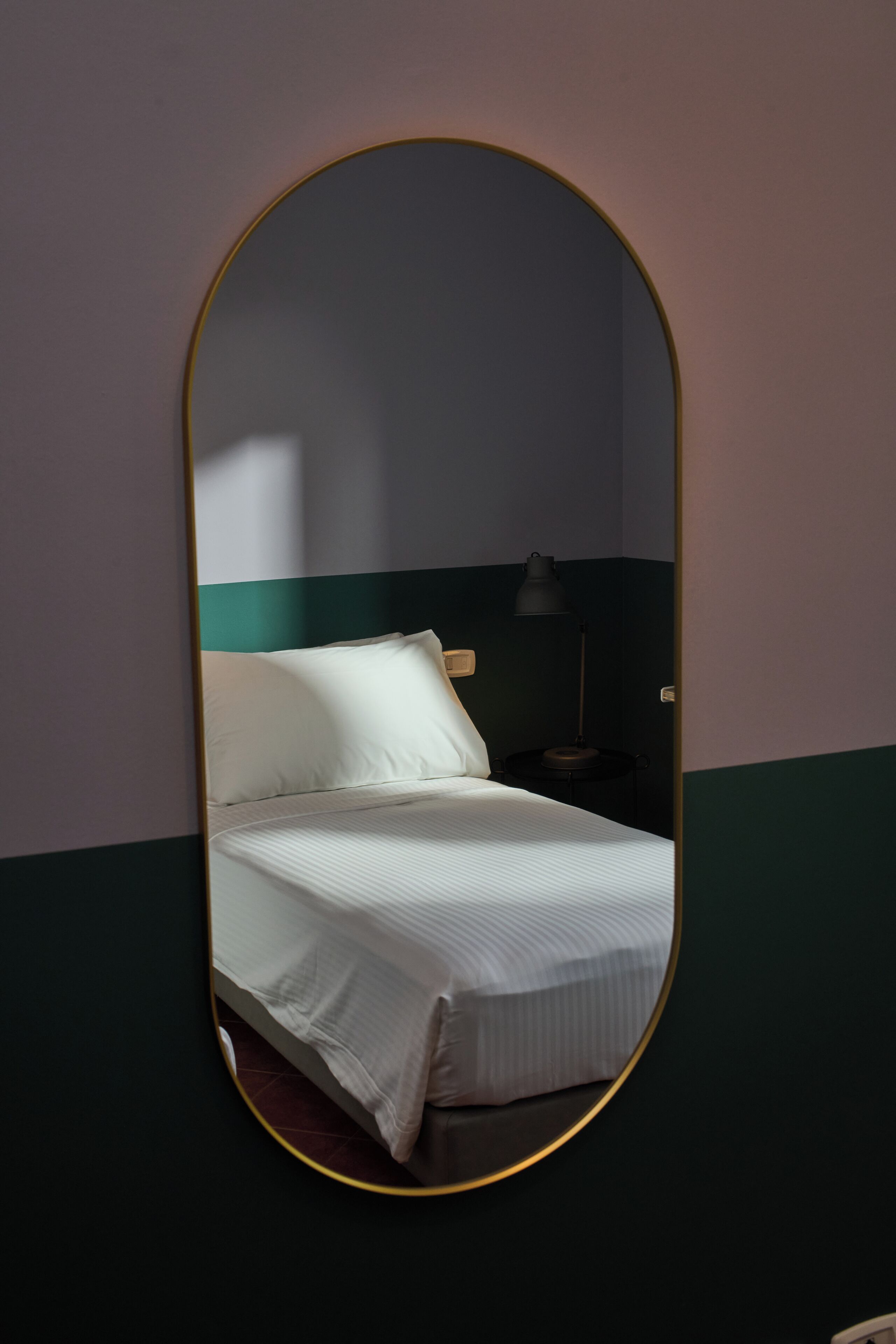 A room with a bed, a nightstand, and a mirror.