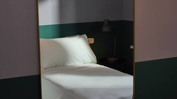 A room with a bed, a nightstand, and a mirror.