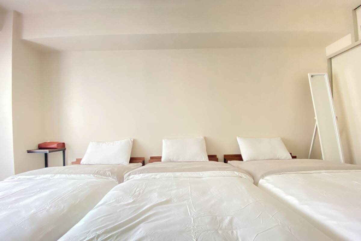 A hotel room with two beds, a small table, and a mirror.