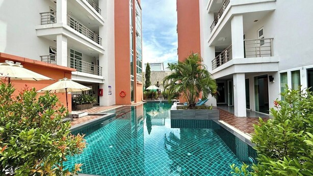 A modern building with a central swimming pool, surrounded by greenery and outdoor seating areas.