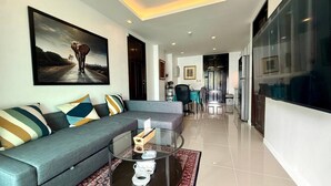 A modern living room with a grey sofa, a glass coffee table, and a large painting of an elephant.