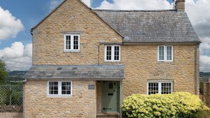 A stone cottage with a green door, two windows on the upper floor, and a small porch. - Murray's Cottage - sleeps 5 guests  in 3 bedrooms (Bourton-on-the-Water)