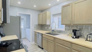Une cuisine moderne équipée d’un lave-vaisselle, d’une cuisinière et d’une fenêtre située au-dessus de l’évier.