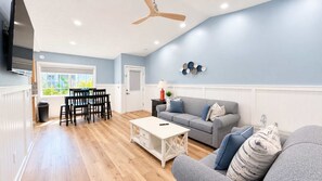 Un salon spacieux avec un canapé gris, une table basse et un coin repas comprenant des chaises et une table.