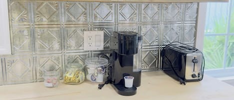 En köksbänk med en kaffebryggare, en brödrost och burkar med olika kryddor och såser.