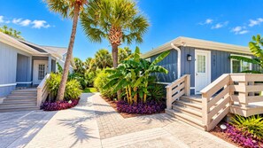 A residential property with a paved driveway, wooden steps, and a variety of tropical plants. - Bright & airy 2BR, 2BA beach retreat A (North Myrtle Beach)