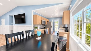 A modern kitchen with wooden cabinets, a black countertop, and a dining area with a black table and chairs. - Bright & airy 2BR, 2BA beach retreat A (North Myrtle Beach)