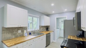 Une cuisine moderne avec des armoires blanches, un plan de travail en bois et un lave-vaisselle encastré.