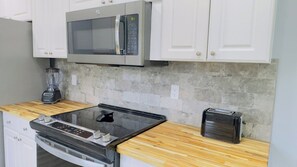 A kitchen with white cabinets, a microwave, a toaster, and a blender on the countertop.