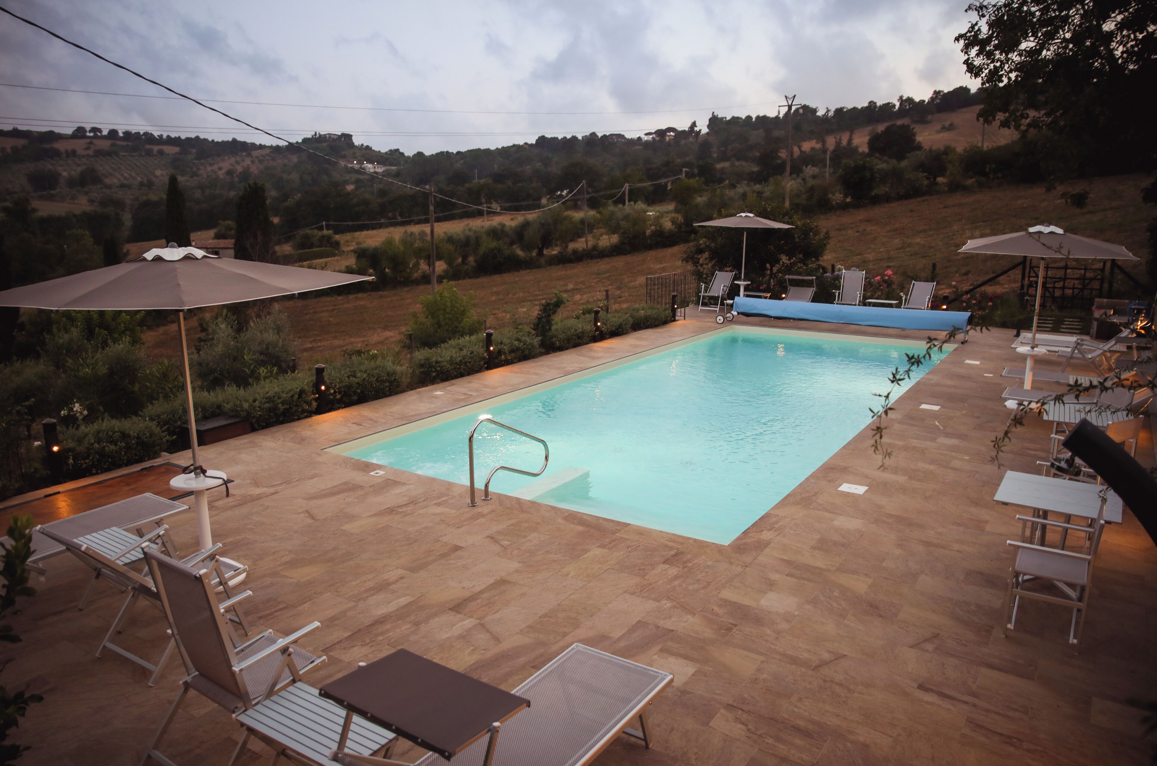 A rectangular pool with a diving board, surrounded by lounge chairs and umbrellas.