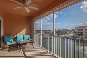 Ein Balkon mit Deckenventilator, einer Couch und einem Tisch.
