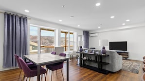 Una sala de estar moderna con comedor, ventanas amplias y un televisor de pantalla plana.