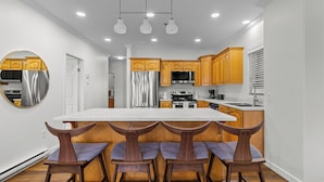 Una cocina moderna con armarios de madera, un refrigerador de acero inoxidable y una isla central con taburetes de bar.