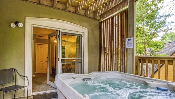 Un área de hidromasaje con terraza de madera, un banco y una puerta que da a una habitación.