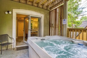 Un área de hidromasaje con terraza de madera, un banco y una puerta que da a una habitación.