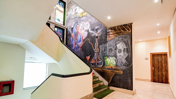 A staircase with a modern design, a mural on the wall, and a wooden door in the background. - BRILL MARINA (Kolkata)