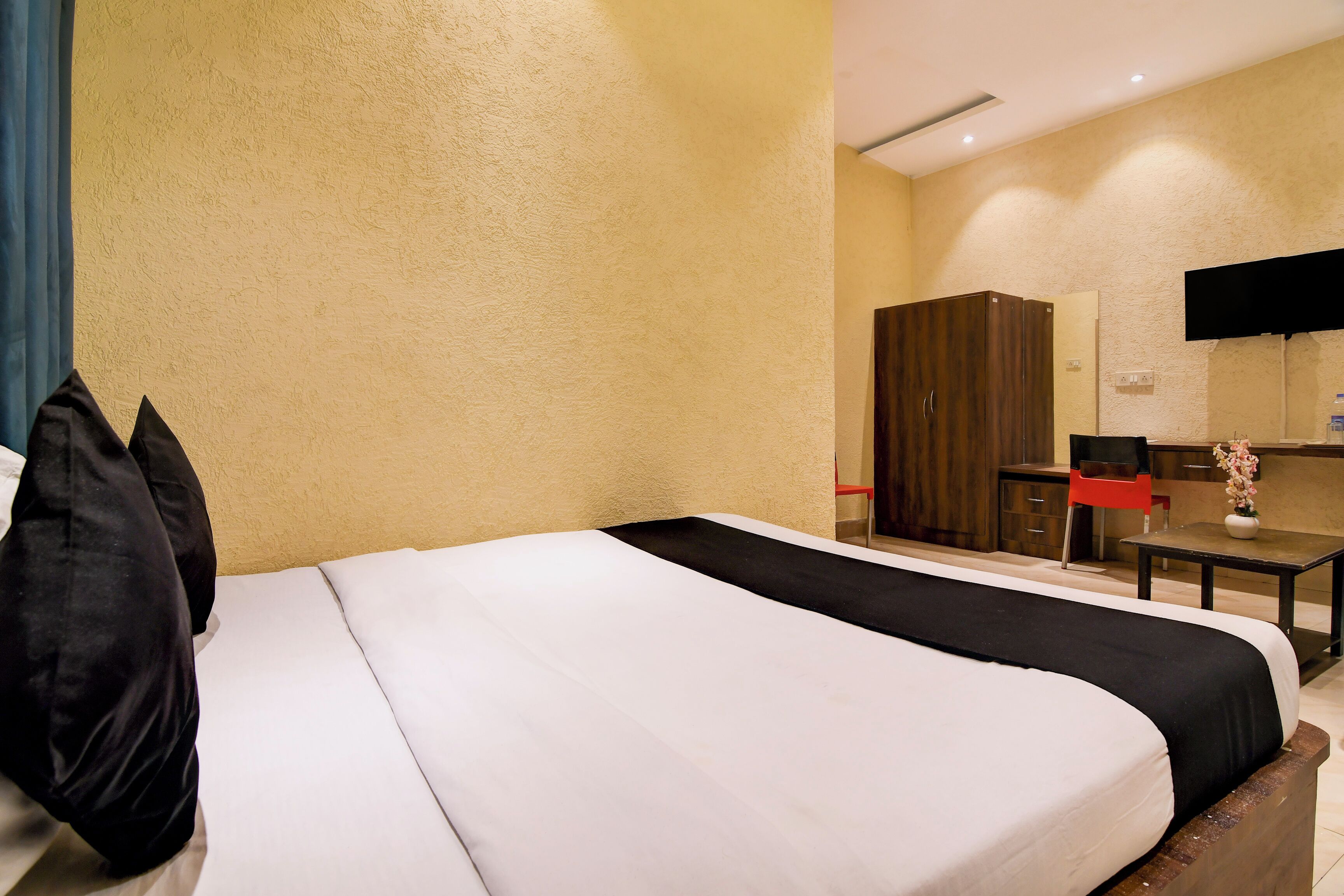 A hotel room with a bed, a wardrobe, a desk, and a mirror.