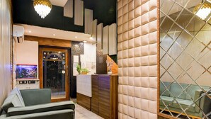 A reception area with a wooden reception desk, a green sofa, and a fish tank. - BRILL MARINA (Kolkata)
