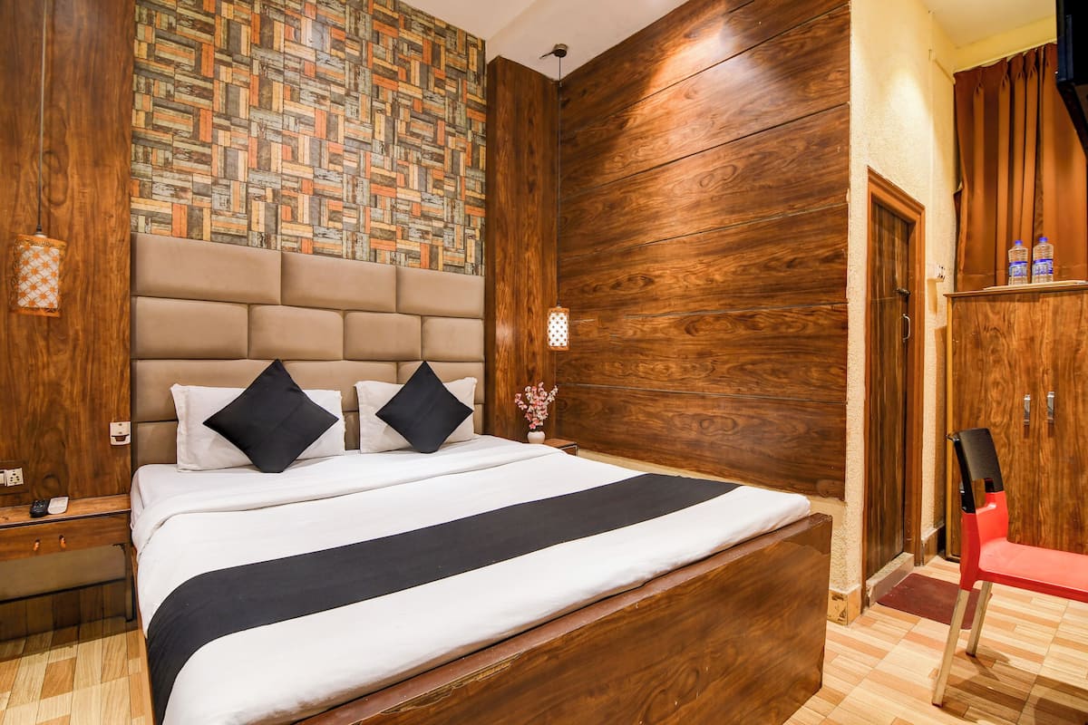 A neatly arranged hotel room with a large bed, wooden headboard, and a patterned wall.