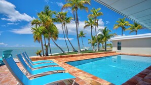 A swimming pool with blue lounge chairs, palm trees, and a view of the ocean. - *NEW!*Paradise Point~VIEWS!~Open Water~Dock~Pool! (Marathon)