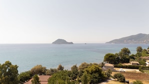 Eine Küstenlandschaft mit Blick auf das Meer, eine kleine Insel und Wohnhäuser.