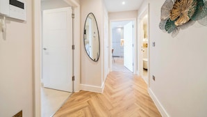A hallway with a white door, a wall-mounted telephone, and a mirror. - Stunning Flat, Hi-Speed WiFi, 55 Inch 4K TV, Desk (Hampshire)