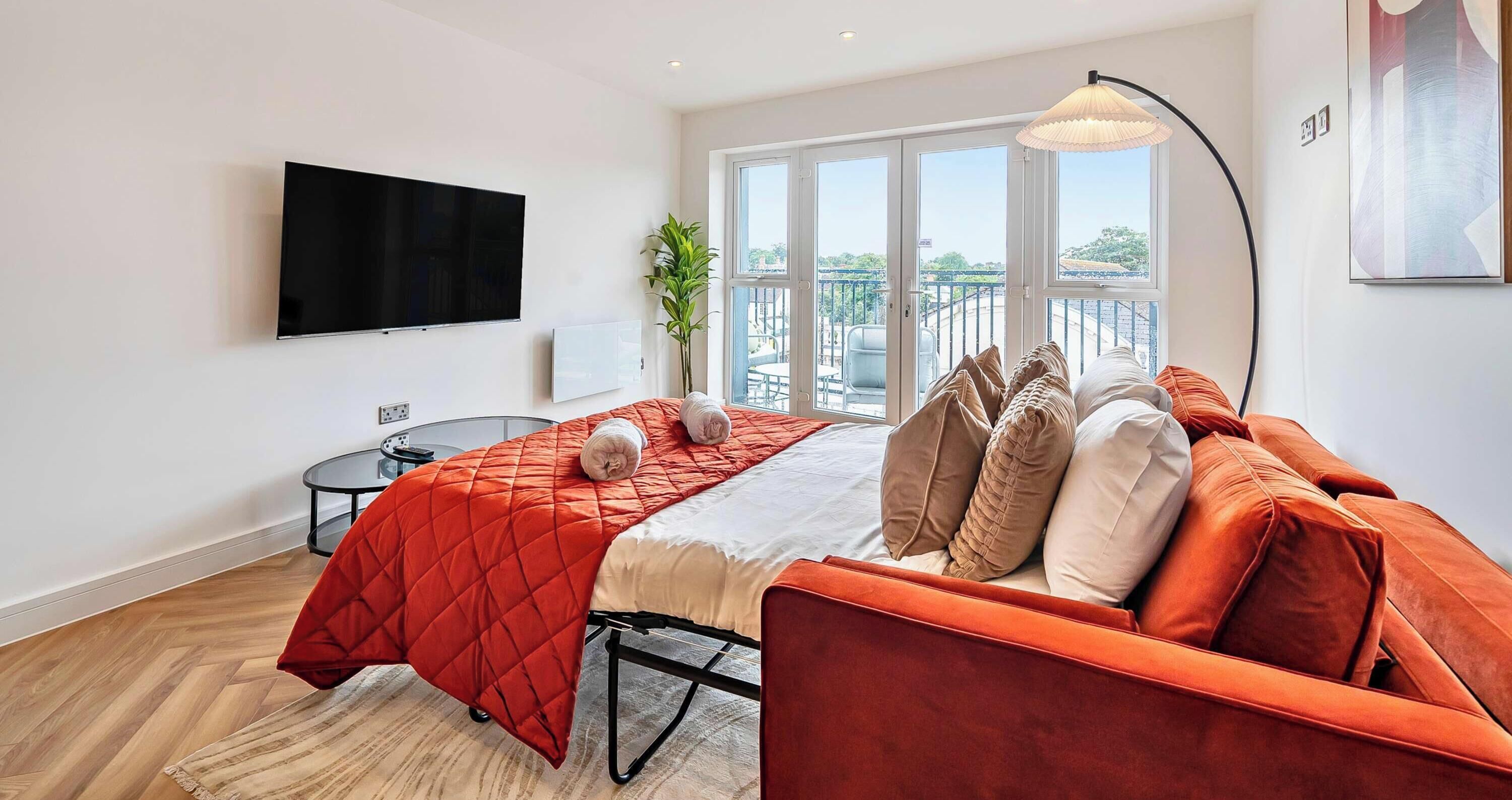 Une chambre moderne avec un lit, une télévision, un balcon donnant sur une belle vue et une petite table.