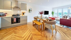 A modern kitchen with a dining area, a red sofa, and a large window. - Penthouse | FREE Parking | Hi-Speed WiFi | Balcony (Farnborough)
