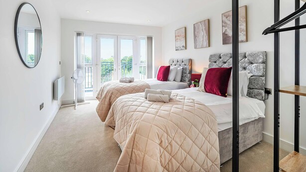 A bedroom with two beds, a large mirror, and a balcony with a view. - Penthouse | FREE Parking | Hi-Speed WiFi | Balcony (Farnborough)