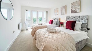 A bedroom with two beds, a large mirror, and artwork on the walls. - Penthouse | FREE Parking | Hi-Speed WiFi | Balcony (Farnborough)