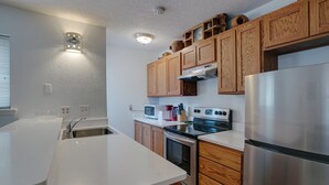 A modern kitchen with wooden cabinets, stainless steel appliances, and a white countertop.