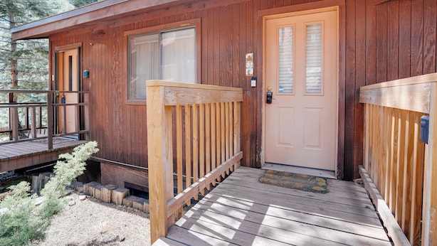 A wooden cabin with a front porch, a door, and a window. - Condo within walking distance of the Chile Express (Angel Fire)