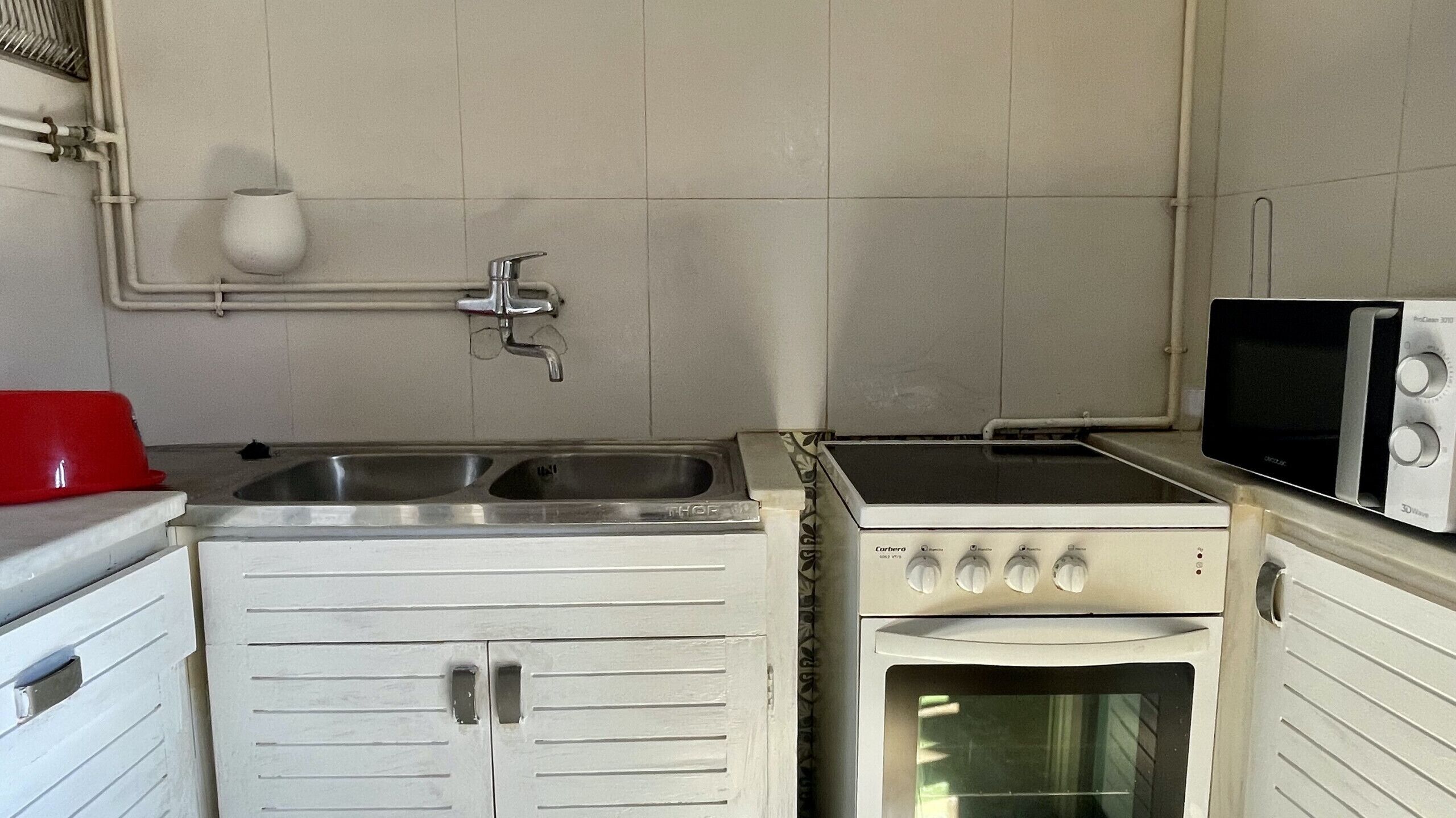 Una cocina compacta con un lavamanos, una estufa y un microondas.