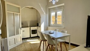 A compact kitchen with a dining area, featuring a stove, oven, and a window with a view of buildings outside.