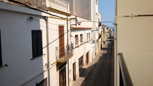 A narrow street lined with white buildings with balconies and shutters. - ENRIC SERRA 54 (L'Escala)