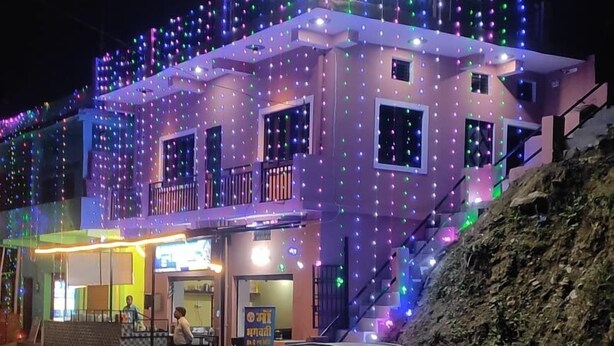 A building with multiple floors and balconies, decorated with colorful lights. - Maa Bhagwati Homestay & Restro (Kosiyakutoli)