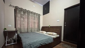 A bedroom with a bed, a bedside table, a small plant, and a wardrobe. - Maa Bhagwati Homestay & Restro (Kosiyakutoli)