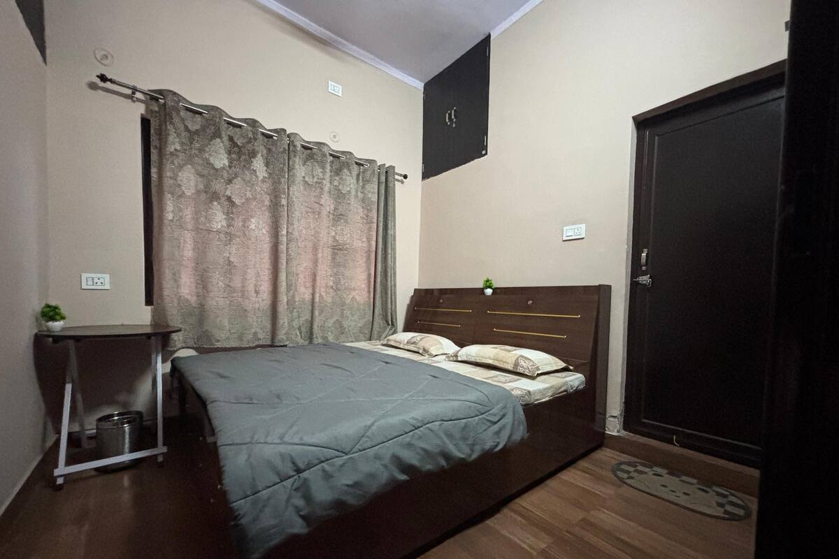 Ein Schlafzimmer mit Bett, Nachttisch, einer kleinen Pflanze und einem Kleiderschrank.