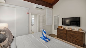 A bedroom with a bed, a TV, a dresser, and a wooden ceiling.