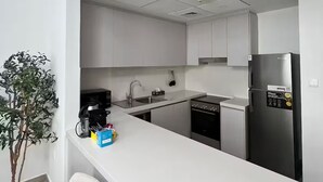 Een moderne keuken met witte kasten, een roestvrijstalen koelkast en een wit aanrecht.